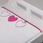 Een leuk wit lakentje met geborduurde hartjes in de kleur roze van het merk Briljant Baby. Een van de hartjes is gevuld met roze stof met stipjes. 