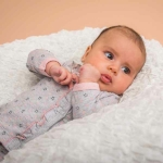 Een schattige grijs overslagshirtje van het merk Dirkje.  Het shirtje heeft roze biezen aan de mouwen, roze drukkers en stiksel. Bedrukt met roze & blauwe sterren. De overslag is afgezet met een rucherand. 