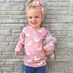 Een hip shirtje met lange mouwen in de kleur roze. Het shirtje heeft een bedrukking van lama's & cactussen. De hals is afgezet met een witte bies. Gemaakt van biologisch katoen.