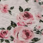 Een schattig grijs rompertje met lange mouwen. Het rompertje heeft ruches op de schouders. Het rompertje is voorzien van een bedrukking van roze rozen. Gemaakt van 100% katoen. 