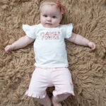 Roze baby short met sierstrikje, ruche rand en hartvormig logootje uit de Flower Power-collectie.