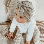 Hier een schattig zandkleurige turban mutsje gemaakt van broderie. Het mutsje heeft aan de voorkant een leuke strik. Door de stof krijgt dit mutsje een mooie en luxe uitstraling.