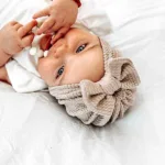 Hier een schattig zandkleurige turban mutsje gemaakt van geweven stof met kabelmotief. Het mutsje heeft aan de voorkant een leuke strik. Door de stof krijgt dit mutsje een speelse en mooie uitstraling.