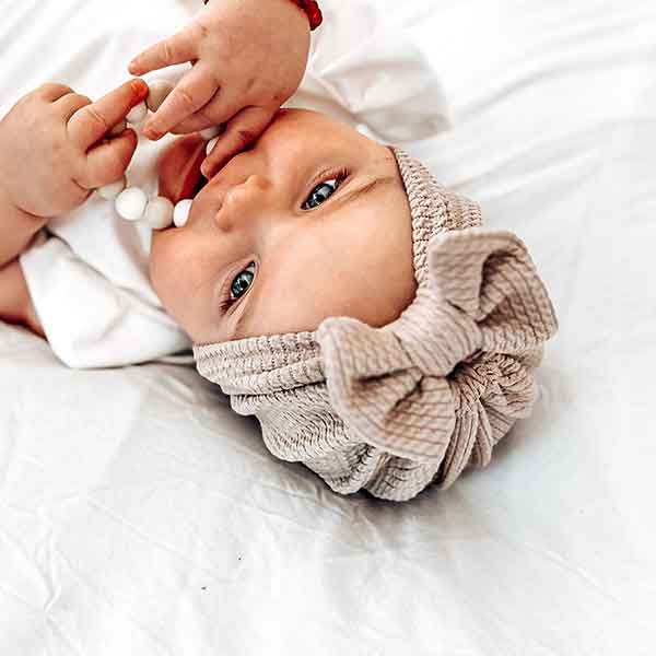 Hier een schattig zandkleurige turban mutsje gemaakt van geweven stof met kabelmotief. Het mutsje heeft aan de voorkant een leuke strik. Door de stof krijgt dit mutsje een speelse en mooie uitstraling.