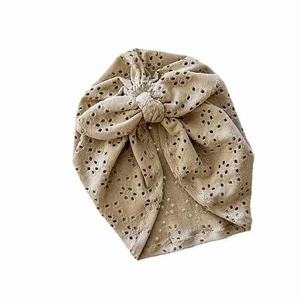 Hier een schattig zandkleurige turban mutsje gemaakt van broderie. Het mutsje heeft aan de voorkant een leuke strik. Door de stof krijgt dit mutsje een mooie en luxe uitstraling.