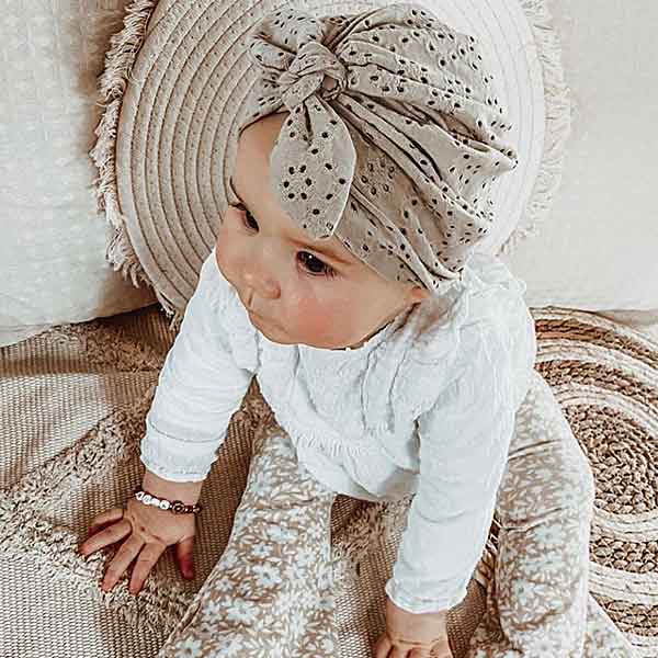 Hier een schattig zandkleurige turban mutsje gemaakt van broderie. Het mutsje heeft aan de voorkant een leuke strik. Door de stof krijgt dit mutsje een mooie en luxe uitstraling.