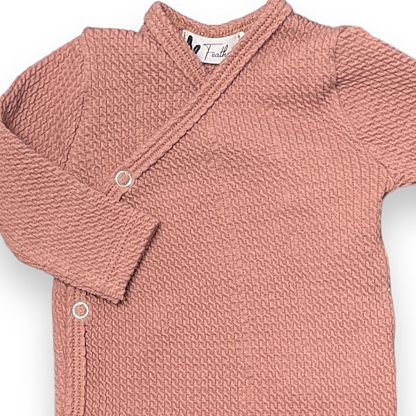 Dit lieve overslagshirt Cable Clay Pink met lange mouw in de kleur oudroze komt uit de collectie Feathers. Dit mooie overslagshirtje is gemaakt van organisch katoen en heeft een fijne kabelmotief. Het overslagshirtje sluit met 2 drukkertjes.