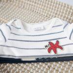 Dit stoere shirt met lange mouw iin de kleur gebroken wit heeft blauwe strepen komt uit de collectie Pirate van Frogs and Dogs. Het shirtje heeft op borsthoogte een leuke zeester in de kleur rood.