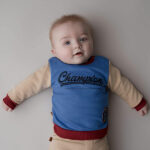 Dit stoere sweater in de kleur blauw, rood & beige komt uit de collectie Handsome Academy van Frogs and Dogs. De sweater heeft op de voorkant groot in het blauw de tekst staan 'Champion'. De letters zijn geborduurd op de sweater en links onderin is het logo van de collectie.