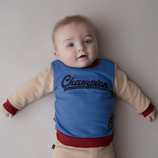 Dit stoere sweater in de kleur blauw, rood & beige komt uit de collectie Handsome Academy van Frogs and Dogs. De sweater heeft op de voorkant groot in het blauw de tekst staan 'Champion'. De letters zijn geborduurd op de sweater en links onderin is het logo van de collectie.