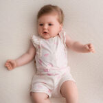 Dit schattige off white - roze gemêleerde overall komt uit de collectie Spring Breeze van Frogs and Dogs. Deze overall heeft is mouwloos en heeft een korte broek. Het pakje heeft een overall print van hartjes. De hals en armsgaten zijn afgezet met een kanten randje. Op de schouders zit een rucherand. Het pakje heeft aan de voorzijde drukkertjes. Op de taillehoogte zit een elastische rand met koord. 