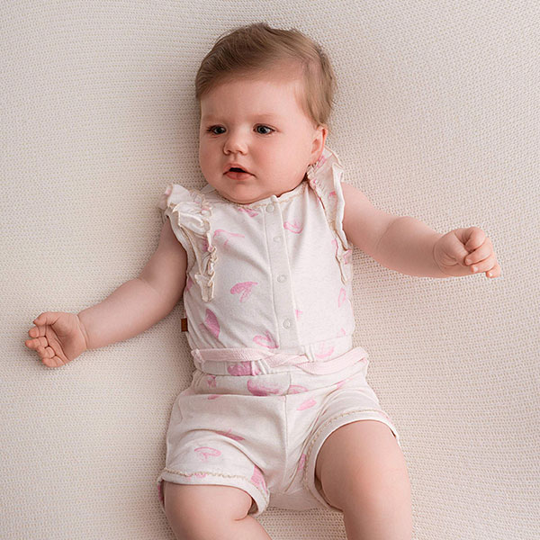 Dit schattige off white - roze gemêleerde overall komt uit de collectie Spring Breeze van Frogs and Dogs. Deze overall heeft is mouwloos en heeft een korte broek. Het pakje heeft een overall print van hartjes. De hals en armsgaten zijn afgezet met een kanten randje. Op de schouders zit een rucherand. Het pakje heeft aan de voorzijde drukkertjes. Op de taillehoogte zit een elastische rand met koord.