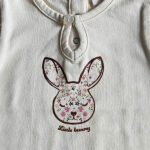 Dit leuke shirtje Little Bunny met korte mouw komt uit Spring Lucky collectie van Frogs and Dogs. Het shirtje heeft een afbeelding van een konijnenhoofd op de voorzijde. De rand van het hoofdje is in de kleur aubergine en in het hoofdje staan diverse kleine bloemetjes geprint.