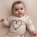 Deze mooie sweater komt uit de collectie Amour van Frogs and Dogs. De sweater is effen beige met op de voorzijde een geborduurd hart in de kleur donkerblauw. De boorden zijn gebreid en effen van kleur en op de schouder zitten 2 knoopjes.