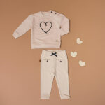 Deze mooie sweater komt uit de collectie Amour van Frogs and Dogs. De sweater is effen beige met op de voorzijde een geborduurd hart in de kleur donkerblauw. De boorden zijn gebreid en effen van kleur en op de schouder zitten 2 knoopjes.