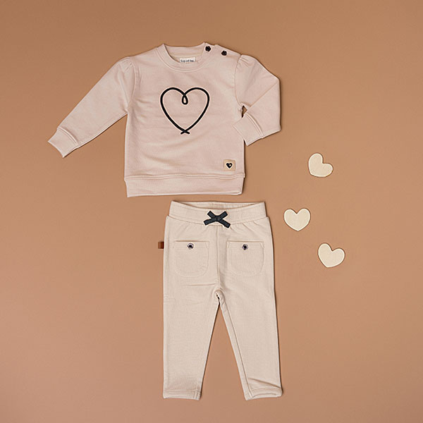 Deze mooie sweater komt uit de collectie Amour van Frogs and Dogs. De sweater is effen beige met op de voorzijde een geborduurd hart in de kleur donkerblauw. De boorden zijn gebreid en effen van kleur en op de schouder zitten 2 knoopjes.