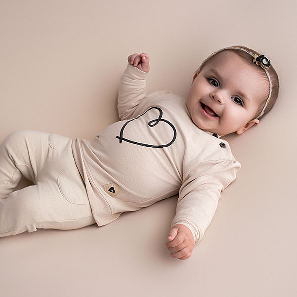 Beige babysweater met donkerblauw geborduurd hartje, gebreide boorden en knoopsluiting op de schouder uit de Amour-collectie van Frogs and Dogs