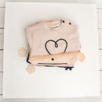 Beige babysweater met donkerblauw geborduurd hartje, gebreide boorden en knoopsluiting op de schouder uit de Amour-collectie van Frogs and Dogs
