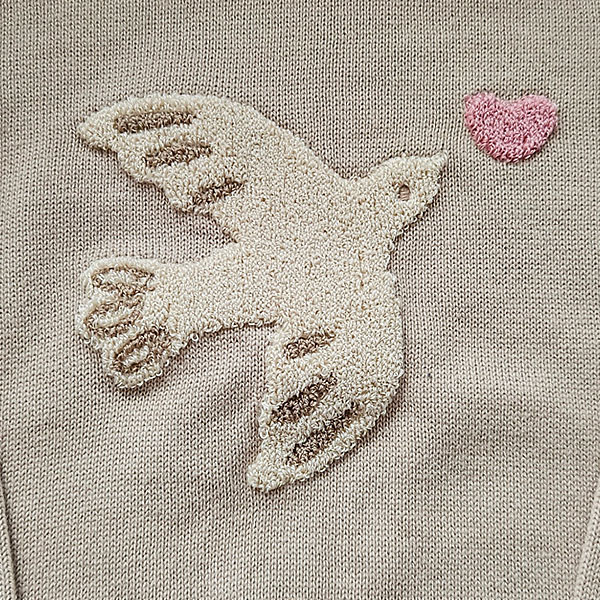 Deze schattige gebreide sweater komt uit de collectie Paloma van Frogs and Dogs. De sweater is effen beige met op de voorzijde een op geborduurd vogel met hartje, van wollige draad. Aan de binnenzijde is vlies gebruik waardoor de huid van je kleintje beschermd wordt. De boorden zijn gebreid en effen van kleur en op de schouder zitten 2 knoopjes.