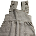 Deze leuke tuinbroek is gemaakt van geruite stof in de kleuren beige en gebroken wit. Deze tuinbroek komt uit de collectie Simply Nice Girl van Frogs and Dogs. Het tuinbroekje heeft aan de voorzijde 2 zakjes en aan de schouderbandjes zitten een ruffle rand. De pijpjes hebben een gezoomde rand met een elastiek. 