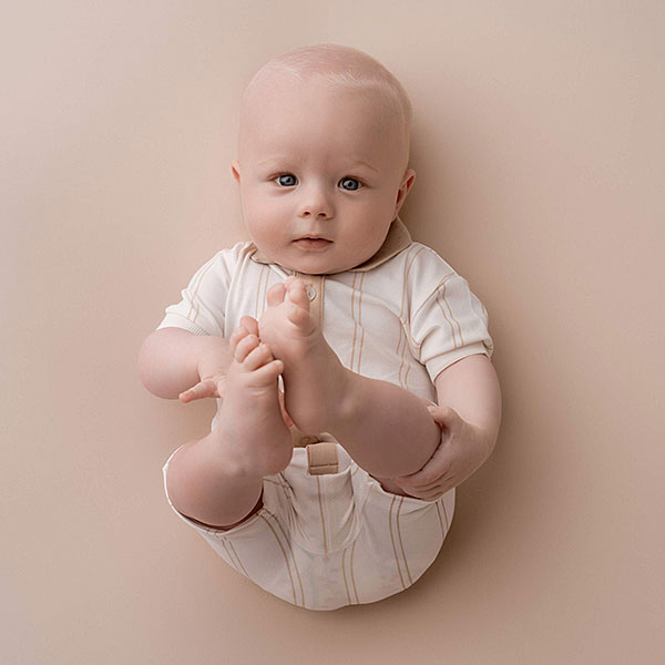 Dit schattige off white gestreepte overall komt uit de collectie Spring Eton van Frogs and Dogs. Deze overall heeft korte mouwen en heeft een polokraagje. Het pakje heeft leuke strepen in de kleur camel. Aan de voorzijde is een sluiting met knoopjes. De hals en de sluiting is gemaakt in de kleur camel. 