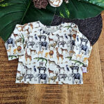 Deze leuke crèmekleurige shirt met lange mouwen komt uit de collectie van ByTasha Exclusive. Het shirtje heeft een een crèmekleurige ondergrond met daarop een bonte print van diverse jungle dieren zoals buffel, giraffe, luipaard, nijlpaard & olifant. De print is een digitale print. Het shirtje heeft een elastische hals en gezoomde boordjes.
