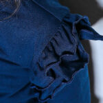 Dit prachtige ruffle baby blouse met unieke houten knoopjes heeft ruffles op de kraag en schouders. En is gemaakt van een zachte elastische kwaliteit wat comfort en warmte biedt voor je kleintje. De boord van de mouwtjes zijn afgewerkt met elastiek waardoor het aankleden nog makkelijker is.