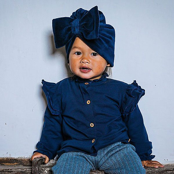 Dit prachtige ruffle baby blouse met unieke houten knoopjes heeft ruffles op de kraag en schouders. En is gemaakt van een zachte elastische kwaliteit wat comfort en warmte biedt voor je kleintje. De boord van de mouwtjes zijn afgewerkt met elastiek waardoor het aankleden nog makkelijker is.