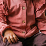 Dit prachtige roze ruffle baby blouse met unieke houten knoopjes heeft ruffles op de kraag en schouders. En is gemaakt van een zachte elastische kwaliteit wat comfort en warmte biedt voor je kleintje. De boord van de mouwtjes zijn afgewerkt met elastiek waardoor het aankleden nog makkelijker is.