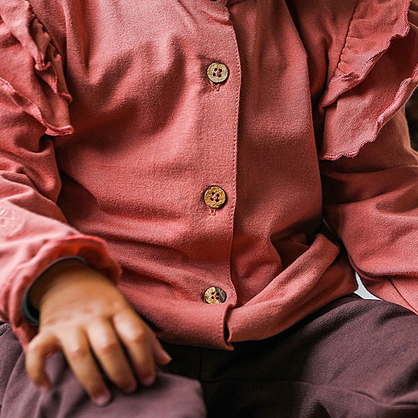 Dit prachtige roze ruffle baby blouse met unieke houten knoopjes heeft ruffles op de kraag en schouders. En is gemaakt van een zachte elastische kwaliteit wat comfort en warmte biedt voor je kleintje. De boord van de mouwtjes zijn afgewerkt met elastiek waardoor het aankleden nog makkelijker is.