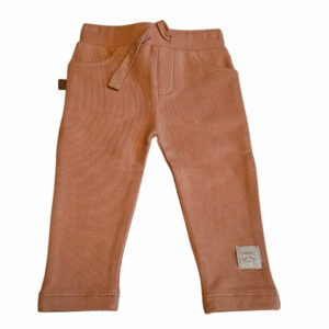 Dit leuke broekje in de kleur caramel komt uit de Raccoon Club collectie van Frogs and Dogs. Het broekje is effen van kleur. Zowel aan de voorzijde als aan de achterzijde zitten zakjes. De elastische tailleband is voorzien van een koordje. De boordjes van de pijpjes zijn gezoomd. Op het linkerpijpje aan de voorzijde zit het logo van de collectie gestikt.