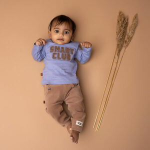 Dit leuke corduroy broekje in de kleur bruin is gemaakt van velvet ribstof komt uit de Smart Club collectie van Frogs and Dogs. Het broekje is effen van kleur en heeft aan de voorzijde 2 steekzakjes. Bij de zakjes zitten ook 2 'knoopjes' op de rand. De tailleband is elastisch met een koord. De pijpjes zijn voor zien van een boordje. Logo van de lijn is geborduurd op het linkerpijpje.