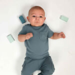 Dit schattige groenblauwe baby t-shirt met korte mouw komt uit de Nice Team collectie van Frogs and Dogs. Het shirtje is effen van kleur en heeft op borsthoogte een klein zakje. Op het zakje is een subtiel dinootje geborduurd, wat zorgt voor een speels detail zonder dat het overheerst.