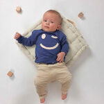 lauwe baby sweater van Frogs and Dogs met grote smileyprint. Zacht, comfortabel en ideaal voor frisse zomerdagen of speelmomenten.