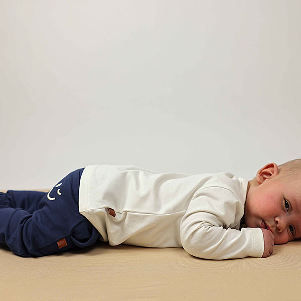 Donkerblauwe baby joggingbroek van Frogs and Dogs met geborduurde smiley. Zacht katoen, comfortabele pasvorm en perfect voor de zomer.