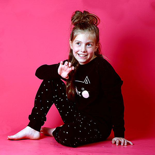 Deze leuke zwarte pyjama Kitty komt uit de collectie van Frogs and Dogs. Deze pyjama bestaat uit een shirt met lange mouwen en een broek met lange pijpen. Het shirtje heeft op de voorzijde een kattenhoofdje in de kleuren roze en wit. Op het broekje staat een overall print van witte hartjes. Deze serie heeft een verbeterde stofkwaliteit waardoor die mooier blijft na het wassen.