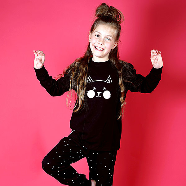 Deze leuke zwarte pyjama Kitty komt uit de collectie van Frogs and Dogs. Deze pyjama bestaat uit een shirt met lange mouwen en een broek met lange pijpen. Het shirtje heeft op de voorzijde een kattenhoofdje in de kleuren roze en wit. Op het broekje staat een overall print van witte hartjes. Deze serie heeft een verbeterde stofkwaliteit waardoor die mooier blijft na het wassen.