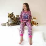 Deze leuke roze pyjama Leopard komt uit de collectie van Frogs and Dogs. Deze serie heeft een verbeterde stofkwaliteit waardoor die mooier blijft na het wassen. Deze pyjama bestaat uit een shirt met lange mouwen en een broek met lange pijpen. De pyjama heeft een overall luipaardenprint in de kleuren roze, zilver, blauw, zwart & paars. Op de voorkant van het shirt staat in het blauw de tekst Wild Girl.