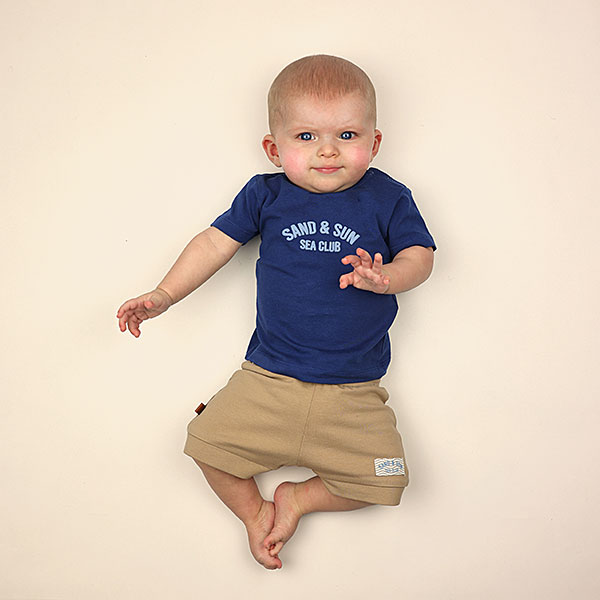 Donkerblauw baby t-shirtje voor jongens van Frogs and Dogs met korte mouwen, lichtblauwe Sea Club opdruk en schouderknoopjes.