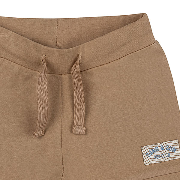 Dit mooie effen korte broekje in de kleur lichtbruin komt uit de collectie Sand and Sun van Frogs and Dogs. Het broekje heeft schattige boordjes aan de pijpjes en een comfortabele tailleband met een koord. Dankzij de neutrale kleur is het eindeloos te combineren met andere items. Als speels detail is het logo van de collectie subtiel op het pijpje gestikt.