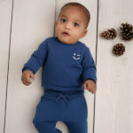 Blauwe baby sweater van Frogs and Dogs met subtiele smiley op de borst. Zacht, comfortabel en ideaal voor frisse zomerdagen.