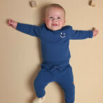 Blauwe baby sweater van Frogs and Dogs met subtiele smiley op de borst. Zacht, comfortabel en ideaal voor frisse zomerdagen.