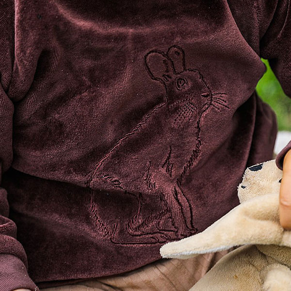 Deze prachtige stijlvolle bruine velourse sweater met een haasje op de voorkant geborduurd heeft lange mouwen en een ronde hals. Gemaakt van 100% katoen en is gemakkelijk aan te trekken dankzij de elastische boorden en de handige diagonale drukknoopjes op de schouders. Deze stoere babytrui is er ook in het lichtblauw.