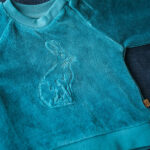 De prachtige stijlvolle velourse sweater met een haasje op de voorkant geborduurd heeft lange mouwen en een ronde hals. Gemaakt van 100% katoen en is gemakkelijk aan te trekken dankzij de elastische boorden en de handige diagonale drukknoopjes op de schouders. Deze stoere babytrui is er in het donker bruin en in het lichtblauw.