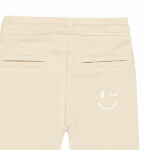 Schattige beige joggingbroek uit de Happy with You collectie van Frogs and Dogs. Het broekje is gemaakt van heerlijk zacht katoen en zit supercomfortabel. De broek heeft twee steekzakjes aan de voorkant en twee nep kontzakjes aan de achterkant. Op een van de achterzakjes zit een geborduurde, blauwe smiley die ondeugend knipoogt — een speels detail!