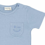 Dit schattige lichtblauwe t-shirt met korte mouwen komt uit de Happy with You collectie van Frogs and Dogs. Het shirtje heeft op borsthoogte een klein zakje, waar een knipogende smile is geborduurd – een vrolijke en speelse detail! De schouder is voorzien van handige drukknoopjes, wat het aan- en uitkleden extra makkelijk maakt.