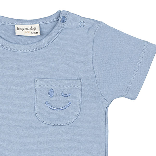 Dit schattige lichtblauwe t-shirt met korte mouwen komt uit de Happy with You collectie van Frogs and Dogs. Het shirtje heeft op borsthoogte een klein zakje, waar een knipogende smile is geborduurd – een vrolijke en speelse detail! De schouder is voorzien van handige drukknoopjes, wat het aan- en uitkleden extra makkelijk maakt.