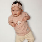 Dit schattige baby haarbandje in de zachte kleur Rose Smoke is een stijlvol accessoire uit de Summer Flowers collectie van Frogs and Dogs. Het baby haarbandje is gemaakt van heerlijk zacht katoen en heeft een effen kleur, wat het geheel een frisse, zomerse uitstraling geeft. Perfect om de outfit van jouw kleine meisje compleet te maken!