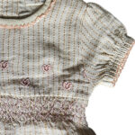 Dit prachtige Gold Glitter jurkje uit de All Collection Summer van Frogs and Dogs straalt pure elegantie uit. Het is gemaakt van crèmekleurige stof met subtiele, gestippelde streepjes met goudglitter. De elastische tailleband, gestikt met roze garen, zorgt voor een mooie pasvorm en extra comfort. Net boven deze rand zijn schattige hartjes geborduurd.