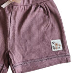 Dit schattige korte broekje, ook wel short, in de kleur Burlwoord komt uit de Summer Flowers-collectie van Frogs and Dogs. Het korte broekje heeft een zachte, effen tint en is gemaakt van comfortabel materiaal, perfect voor warme zomerdagen. De elastische tailleband biedt een fijne pasvorm en is afgewerkt met een roze strikje. Boven de zoom van het pijpje zit een leuk kanten randje verwerkt. Een perfecte mix van stijl en comfort voor een zomerse look!